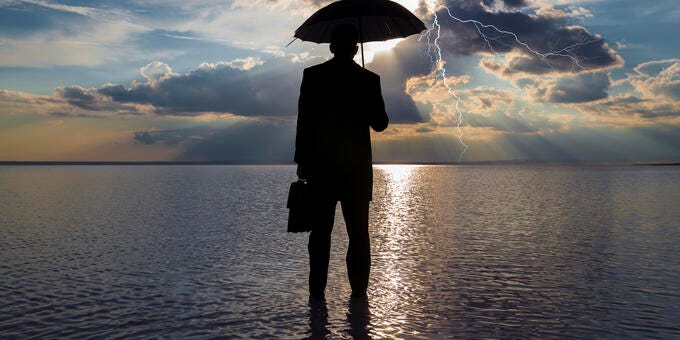 a person standing in the water holding an umbrella