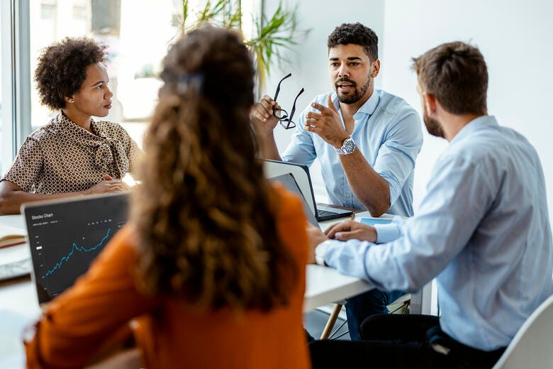 a group of people sitting at a table looking at a laptop