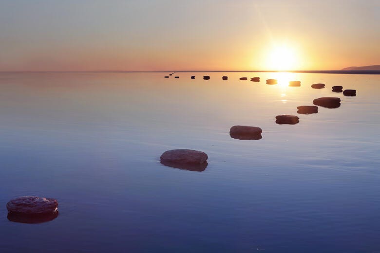 a body of water with rocks in it and the sun setting