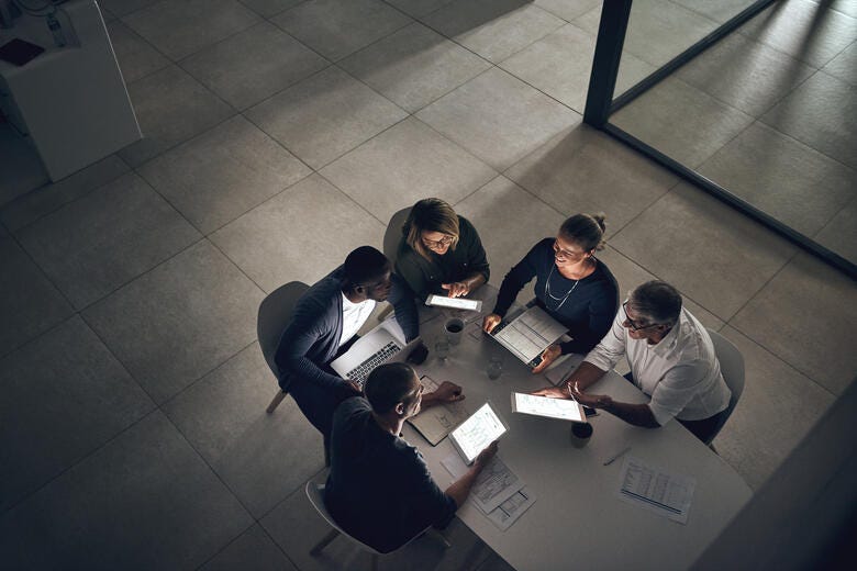 a group of people sitting around a table looking at papers